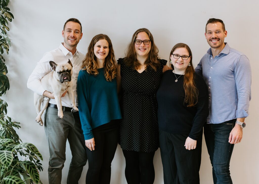 Picture of 5 people and a dog in a bright office reception area.
